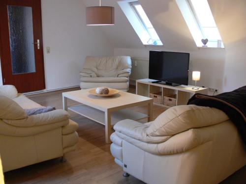 ベルゲン・アウフ・リューゲンにあるFerienwohnung Monimaのリビングルーム(椅子2脚、テーブル、テレビ付)