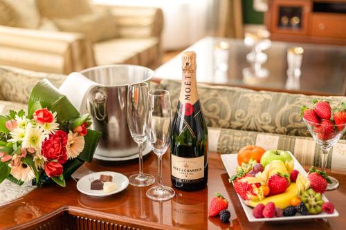 a bottle of wine and glasses on a table with fruit at Spa Hotel Imperial in Karlovy Vary