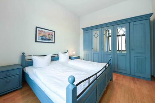ヘリングスドルフにあるVilla Sanssouci Wohnung 5の青いベッドルーム(白いシーツを使用した大型ベッド1台付)
