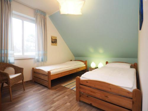 a bedroom with two beds and a chair and a window at Ferienhaus Sonneninsel 5c in Korswandt