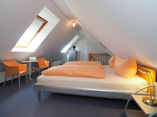 ein Bett mit orangefarbenen Kissen in einem Dachzimmer in der Unterkunft (85) Villa Annelies 02 in Ahlbeck