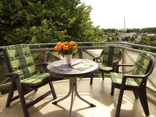 a table with two chairs and a vase of flowers on a balcony at Haus auf der Höhe - Panorama in Heringsdorf