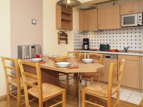 una cucina con tavolo in legno, sedie e un angolo cottura. di Wohnung am Schloonsee B4 a Heringsdorf