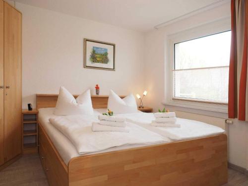 Cette chambre comprend un grand lit blanc et une fenêtre. dans l'établissement Haus Dünenweg 28, à Heringsdorf