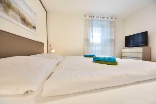 ヘリングスドルフにあるForum Marinar 14の白いベッド(枕2つ付)、テレビが備わります。