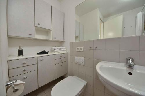 ein weißes Bad mit einem WC und einem Waschbecken in der Unterkunft Forum Marinar 20 in Heringsdorf