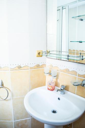 a bathroom with a white sink and a mirror at Vila Smarald Apartments in Neptun