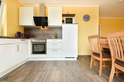 - une cuisine avec des placards blancs, une table et un four micro-ondes dans l'établissement Sonnenpark 04, à Korswandt