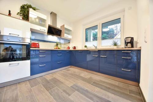 コルスヴァントにあるSonnenpark 05の青いキャビネットと窓付きの広いキッチン