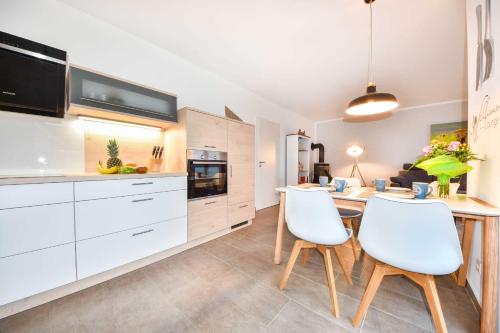 a kitchen with white cabinets and a table and chairs at Sonnenpark 15 in Korswandt