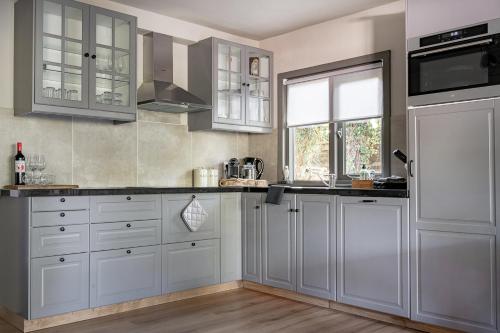 a kitchen with white cabinets and a window at Gieters Geluk in Giethoorn