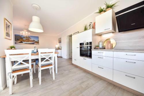 una cocina con armarios blancos y una mesa con sillas. en Sonnenpark 12, en Korswandt