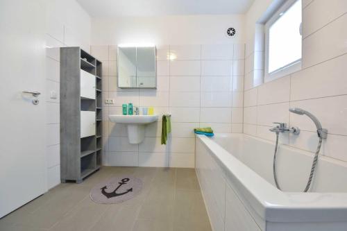 ein weißes Badezimmer mit Badewanne und Waschbecken in der Unterkunft Haus Neuhof 01 in Heringsdorf
