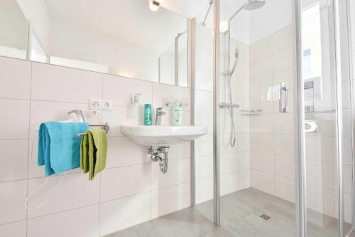 a white bathroom with a sink and a shower at Kleines Ferienhaus Kuschelnest in Kamminke