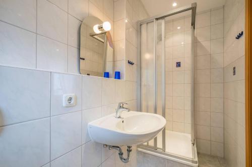een witte badkamer met een wastafel en een douche bij Villa Mirja 02 in Ahlbeck