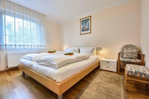 ein Schlafzimmer mit einem Bett, einem Stuhl und einem Fenster in der Unterkunft Haus an der Düne Wohnung 04 in Heringsdorf