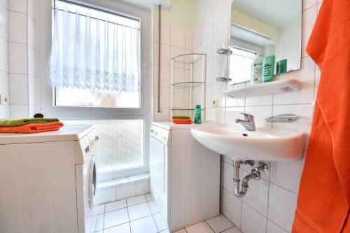 ein weißes Bad mit einem Waschbecken und einem Fenster in der Unterkunft Haus an der Düne Wohnung 04 in Heringsdorf
