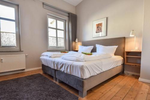 ein Schlafzimmer mit einem großen Bett und zwei Fenstern in der Unterkunft Gartenhaus Ostseevilla 07 in Bansin