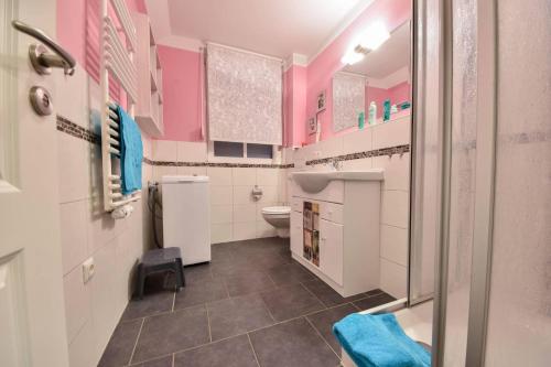 baño con paredes de color rosa y blanco y aseo en Ferienhaus Waldhaus en Korswandt