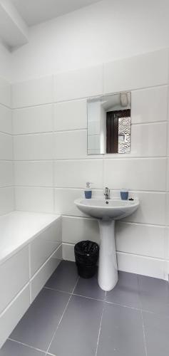 a white bathroom with a sink and a mirror at Casa Crown in Braşov