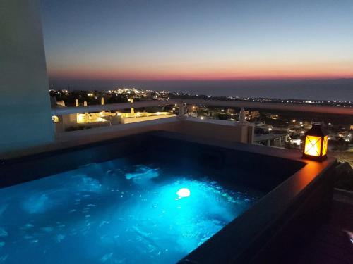 a swimming pool on the roof of a building at night at Kiklamino Sunset Studios in Oia