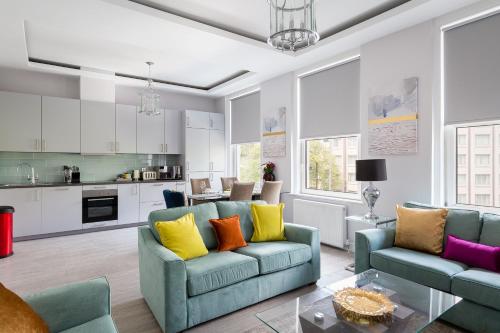 a living room with two blue couches and a kitchen at Cromwell road apartments in London
