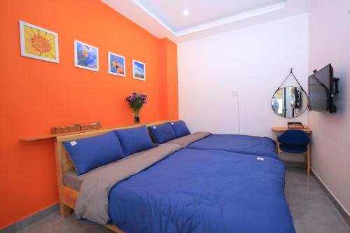 ein Schlafzimmer mit einem blauen Bett und einer orangefarbenen Wand in der Unterkunft Maison de Fleurs - Ngôi Nhà Hoa in Da Lat