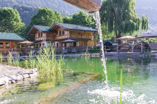 a fountain in front of a lake with houses at Feelfree Nature Resort in Oetz