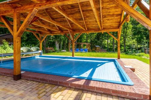 duży basen pod drewnianym pawilonem w obiekcie Penzion Kokorin Forest Villa w mieście Konrádov