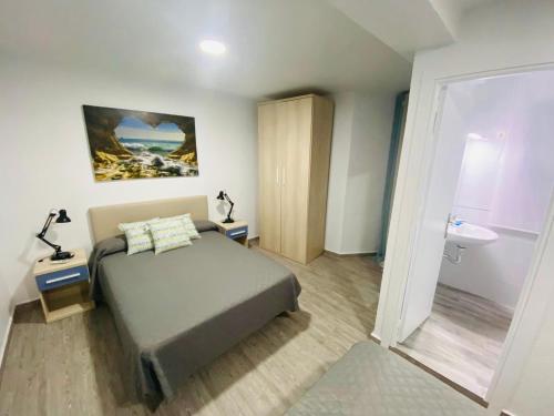 een slaapkamer met een bed en een badkamer met een wastafel bij Pension Ramonetero in Águilas