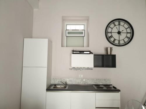 eine Küche mit einem Waschbecken und einer Uhr an der Wand in der Unterkunft Casa Bolle Ortigia in Syrakus