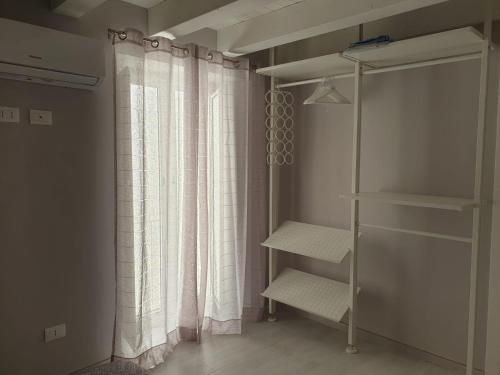 ein Schrank mit einem Duschvorhang und einem Regal in der Unterkunft Casa Bolle Ortigia in Syrakus
