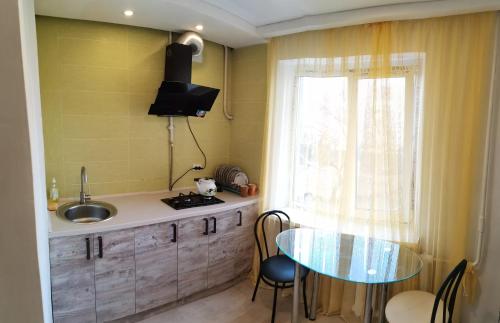 a kitchen with a table and a sink and a window at Spas`ka Apartment in Peresadovka
