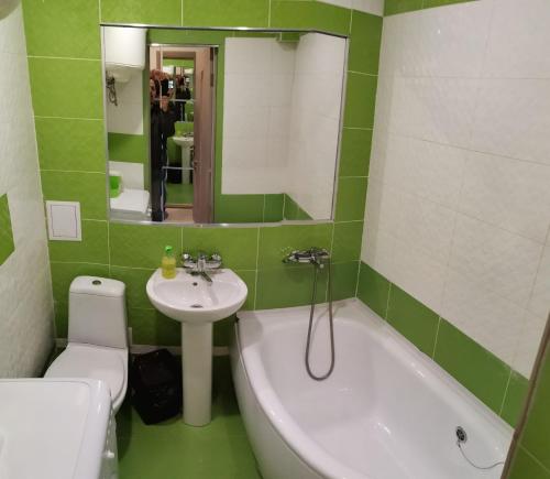 een groene en witte badkamer met een bad en een wastafel bij Spas`ka Apartment in Peresadovka