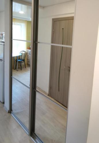 une porte coulissante en verre menant à une salle à manger avec une table. dans l'établissement Spas`ka Apartment, à Peresadovka