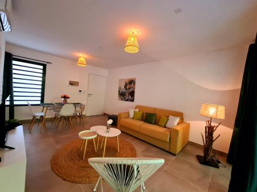 a living room with a couch and a table at Appartement le Cattleya à proximité du lagon de l'Ermitage les bains in Filaos