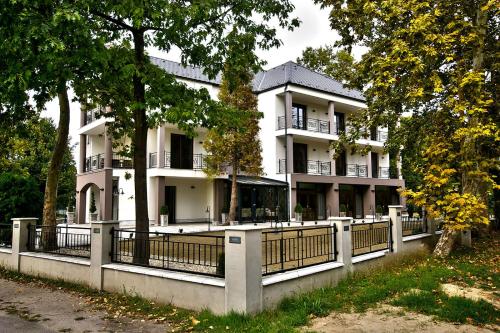 a large white building with a fence in front of it at Boutique Hotel Divina in Harkány