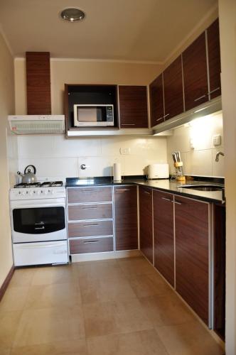 a kitchen with wooden cabinets and a microwave at 11 Peyret Rent Aparts in Colón