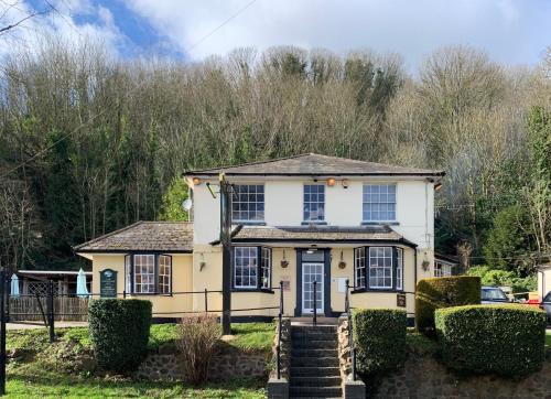 a yellow and white house with trees in the background at The Railway Inn in Malvern Wells