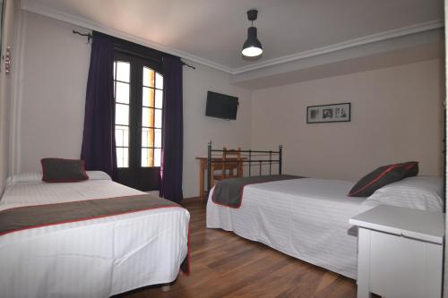 a bedroom with two beds and a window at Hostería El Bodegón De Gredos in Arenas de San Pedro