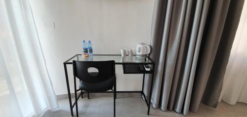 a glass table with a black chair in a room with curtains at InCentroScalea B&B in Scalea