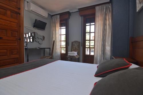 a bedroom with a large white bed and windows at Hostería El Bodegón De Gredos in Arenas de San Pedro