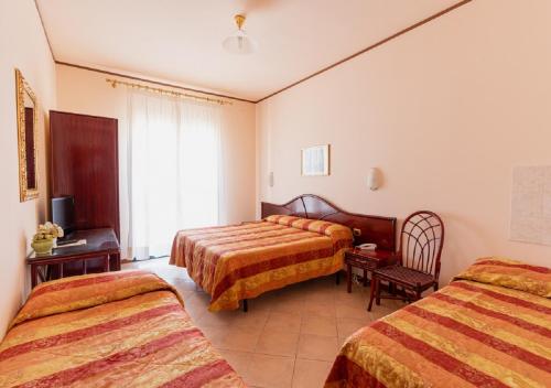 a hotel room with two beds and a television at Hotel Villa Delle Rose in Oristano