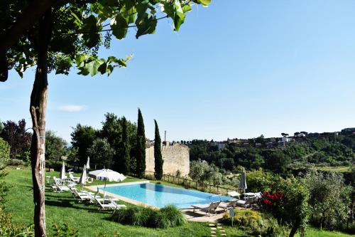 - une piscine avec des chaises et des parasols dans un champ dans l'établissement Podere La Strega, à Sienne