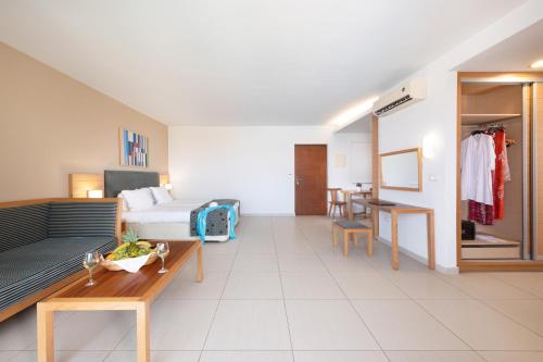 a living room with a bed and a table at Iolida Beach by Smile Hotels in Agia Marina Nea Kydonias