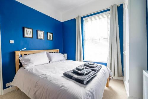 een blauwe slaapkamer met een bed met handdoeken erop bij 3 Darnborough Street in York