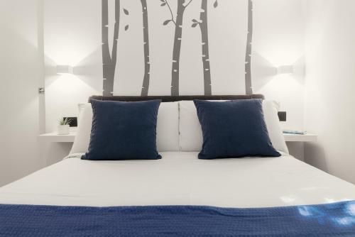 Cama con almohadas azules y árboles en el fondo en Domus Quiritum Elite, Vatican luxury apartment, en Roma