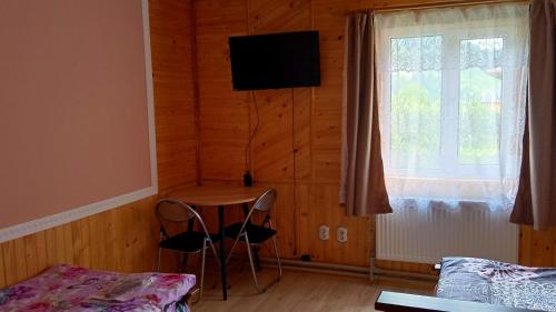 a room with a table and two chairs and a window at Мамина Хата in Mykulychyn