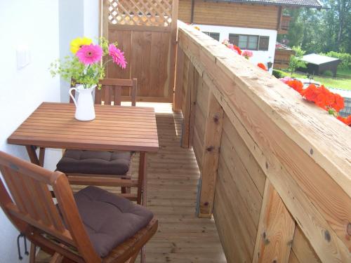 a wooden balcony with a table and flowers on it at Ferienwohnung Fritz 2 Obergeschoss in Stuhlfelden