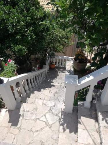 a white bench in a garden with potted plants at Petros Penthouse in Parga